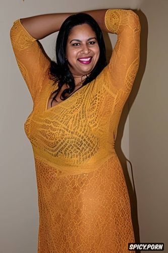 a smiling thick woman with long, wearing a mustard yellow ethnic outfit adorned with intricate embroidery and embellishments she stands with her arms crossed in front of her