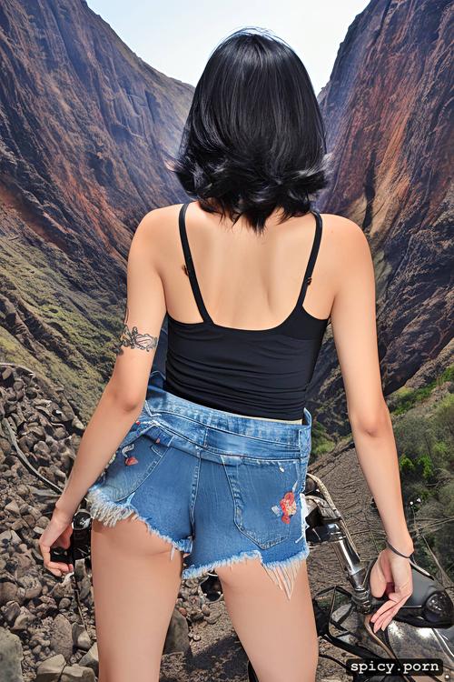 denim shorts, rose tattoo on her arm, black boots, on a mountain road