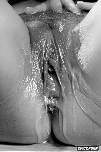 pearl like droplets of clear liquid oozing slowly out of the center of the vulva as the camera zooms in